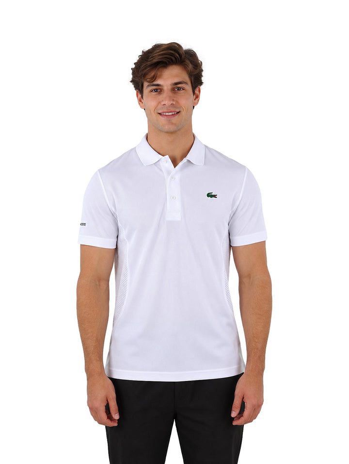 Hombre vistiendo una playera polo Lacoste de color blanco con cuello y botones.