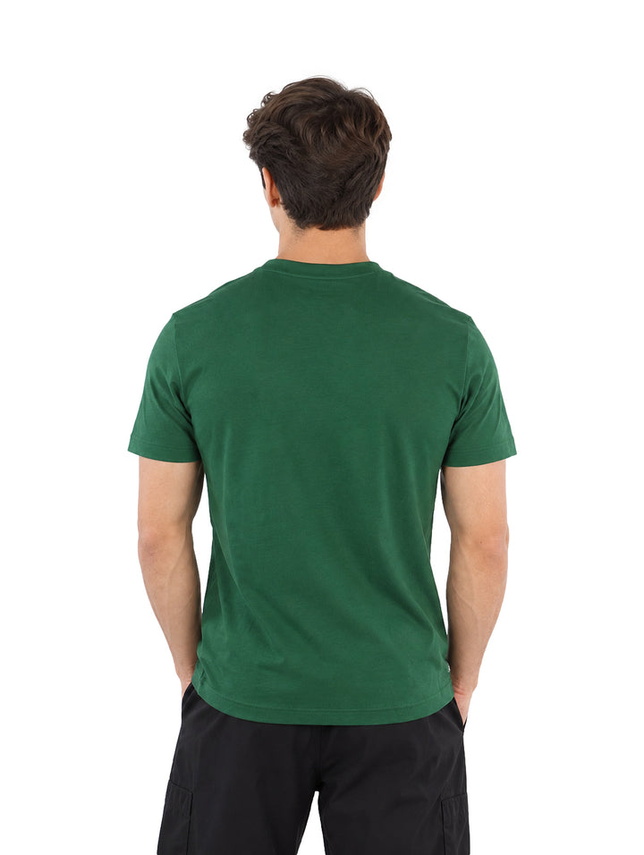 Hombre vistiendo playera Lacoste color verde de manga corta con texto frontal y shorts negros.