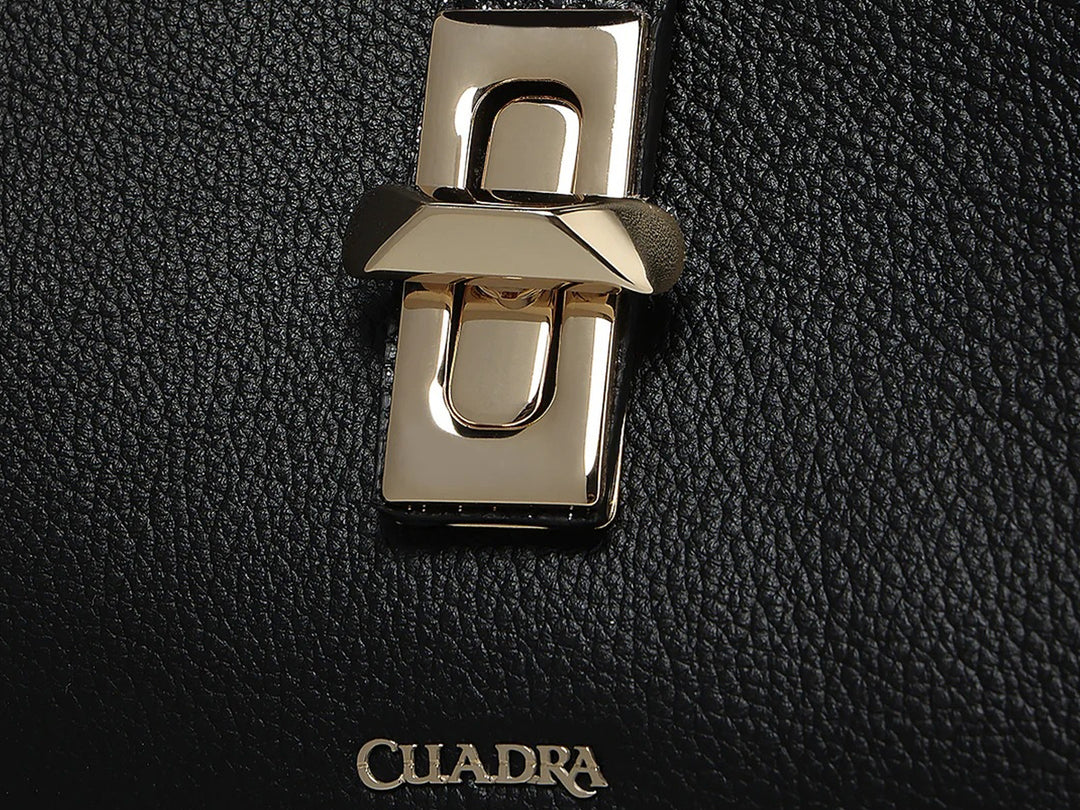 Bolso hobo de cuero negro con textura rugosa y detalle metálico plateado en el centro, marca Cuadra.