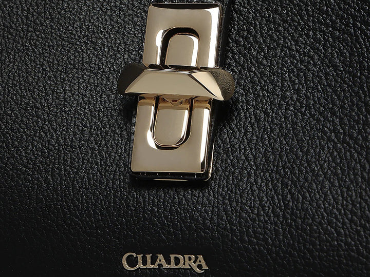 Bolso hobo de cuero negro con textura rugosa y detalle metálico plateado en el centro, marca Cuadra.