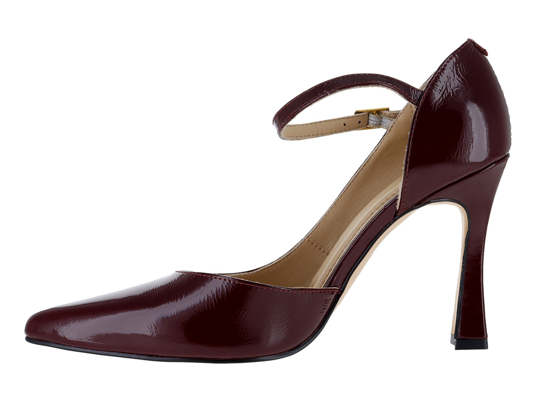 Zapato de tacón cerrado color vino con acabado brillante y correa al tobillo con hebilla dorada.