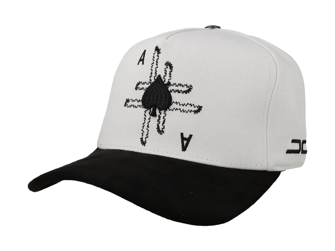 Gorra blanca con visera negra y diseño bordado de as de picas en la parte frontal.