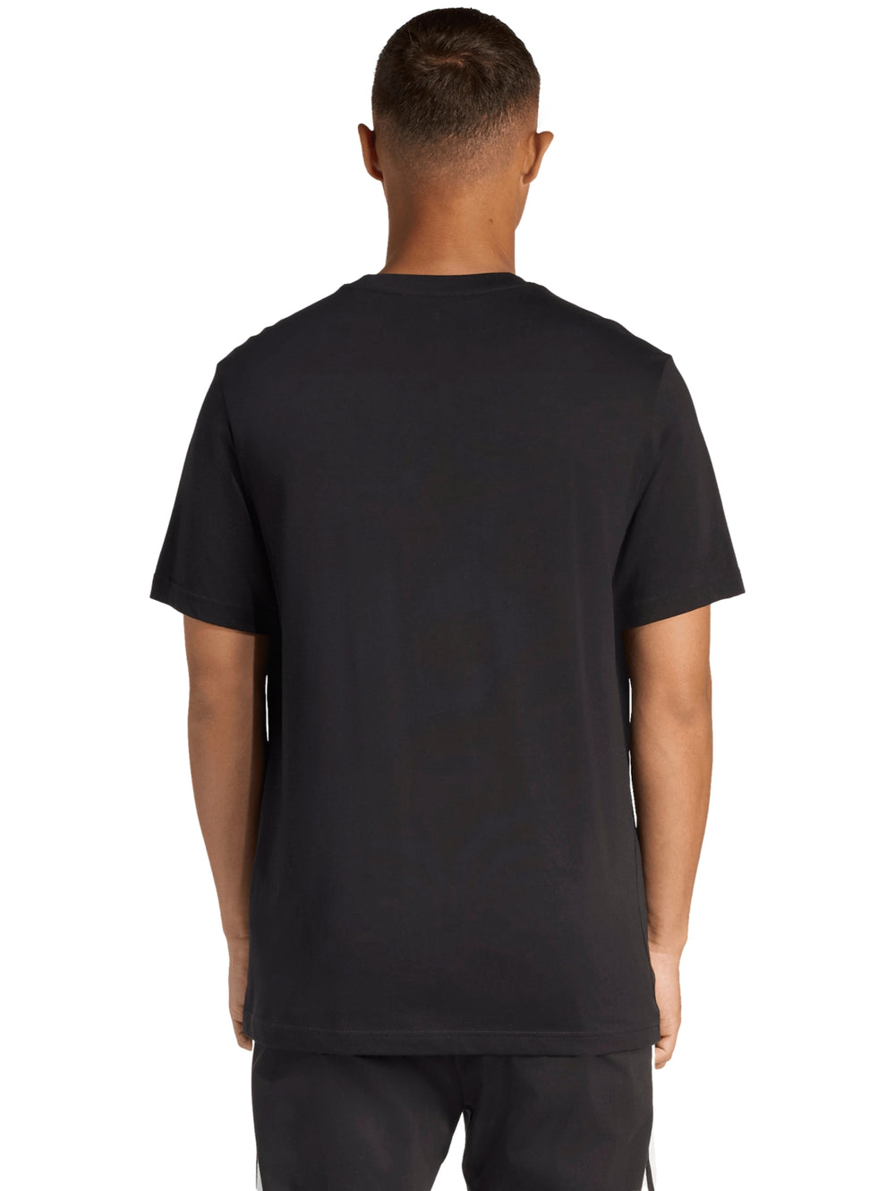 Hombre vistiendo una camiseta deportiva Adidas de color negro con un detalle gráfico en el pecho.
