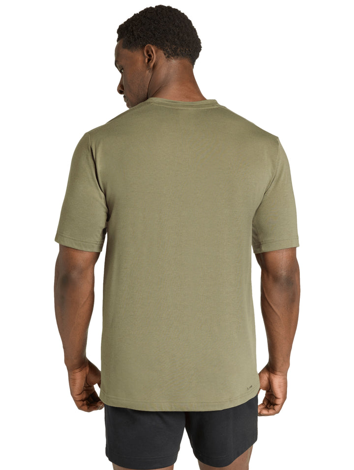 Hombre vistiendo una camiseta deportiva Adidas de color verde oliva con logo pequeño en el pecho.