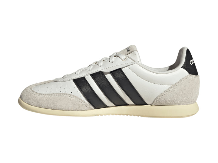 Tenis Adidas blancos con tres franjas negras y detalles en color crema en la punta y el talón.
