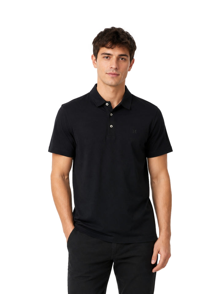 Hombre vistiendo una playera polo color negro de la marca Hurley sobre fondo blanco.