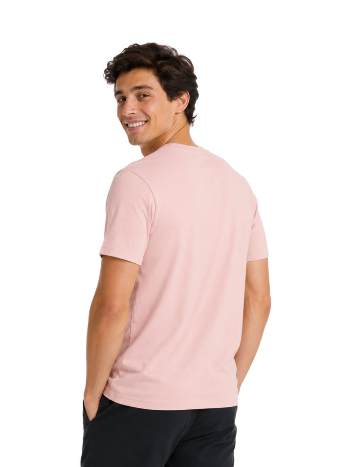 Hombre vistiendo una playera Hurley de color rosa pálido con logotipo en el pecho.