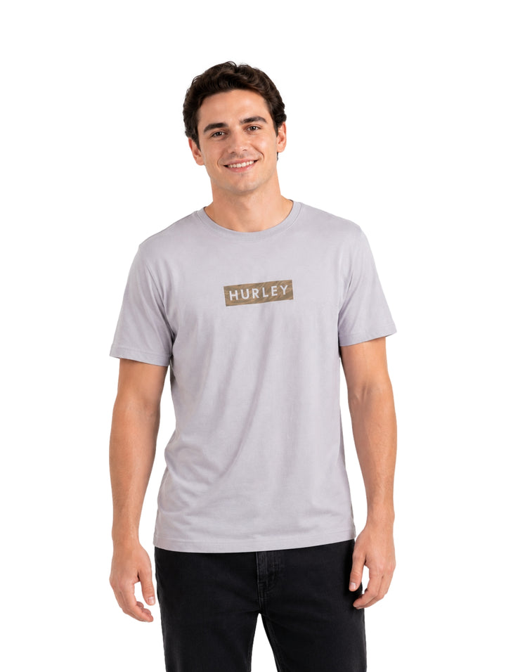 Hombre vistiendo playera Hurley color gris claro Light Asteroid de manga corta y cuello redondo.