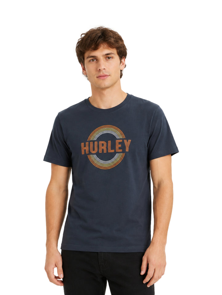 Hombre vistiendo playera Hurley color destroyer con gráfico circular en el pecho.