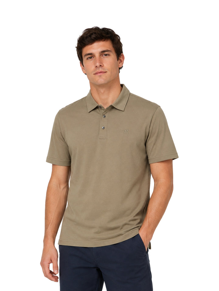 Hombre vistiendo playera polo Hurley color iguana de manga corta y cuello con botones.
