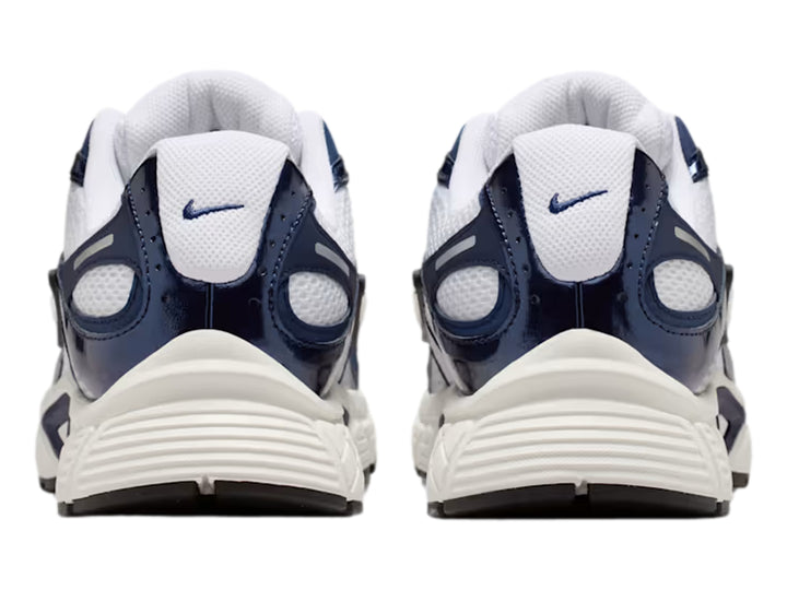 Tenis Nike color blanco y azul marino con detalles plateados y suela blanca robusta.
