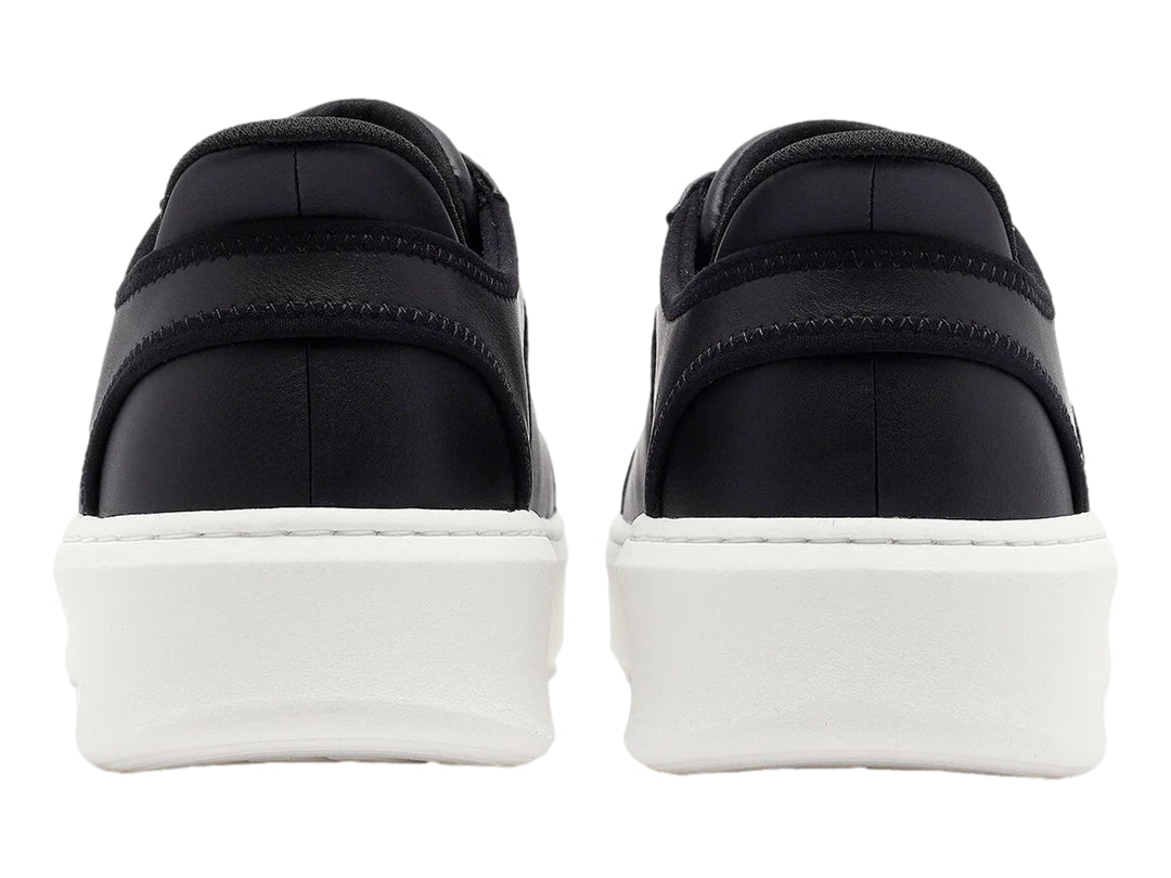 Tenis Skechers color negro con suela blanca gruesa y cordones negros.