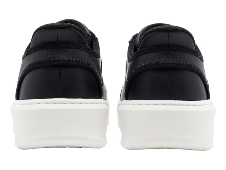 Tenis Skechers color negro con suela blanca gruesa y cordones negros.