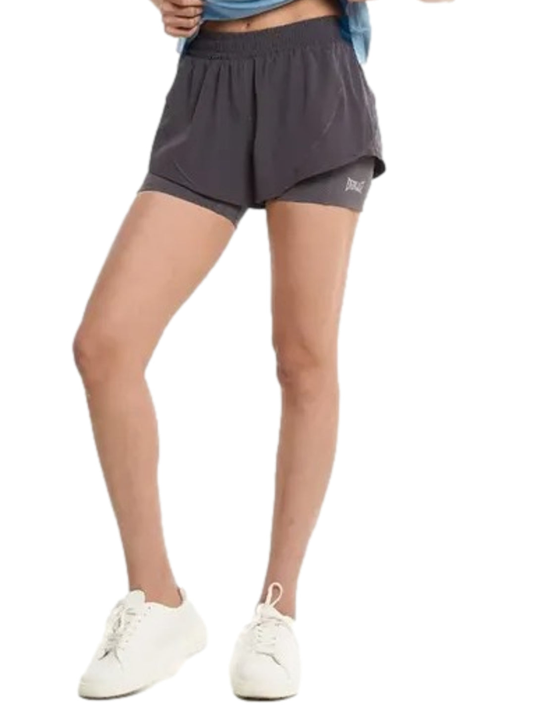 Mujer vistiendo shorts deportivos color gris de la marca Everlast.