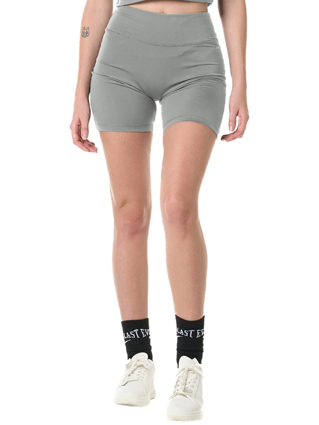 Mujer vistiendo mallas deportivas cortas color gris de cintura alta marca Everlast.
