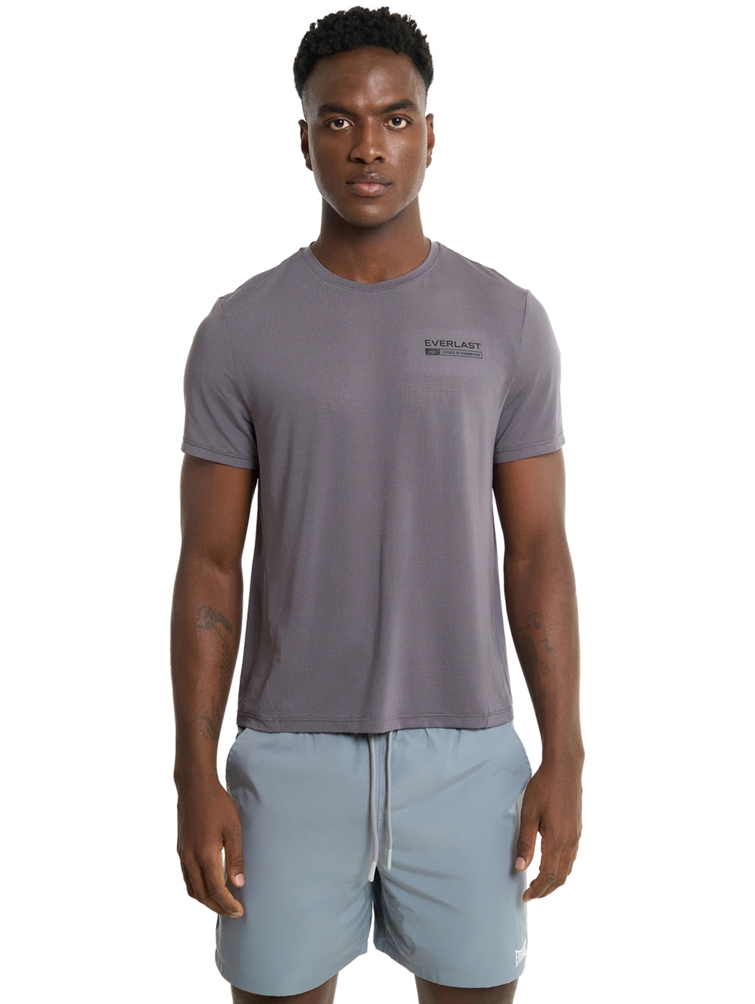 Hombre modelando camiseta deportiva gris oscuro y shorts gris claro de la marca Everlast.