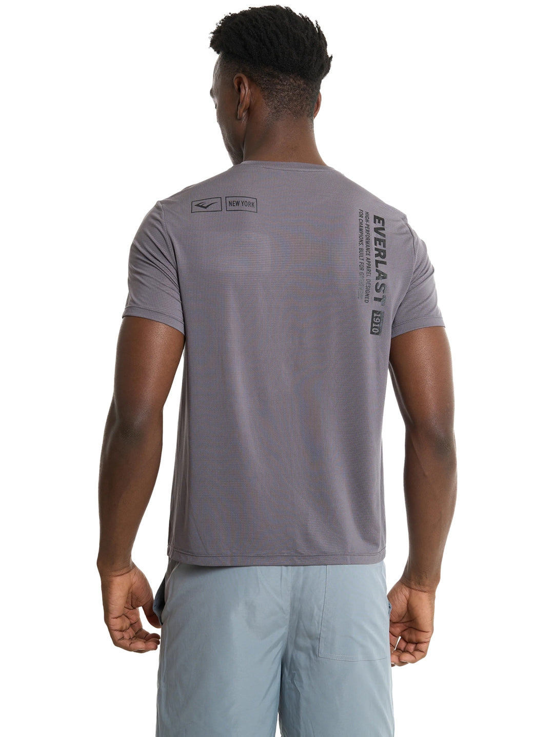 Hombre modelando camiseta deportiva gris oscuro y shorts gris claro de la marca Everlast.