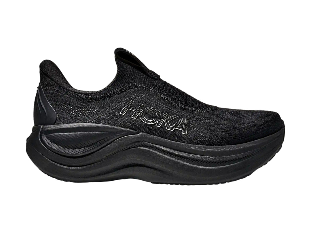 Tenis deportivos Hoka color negro, diseño sin agujetas y suela gruesa.