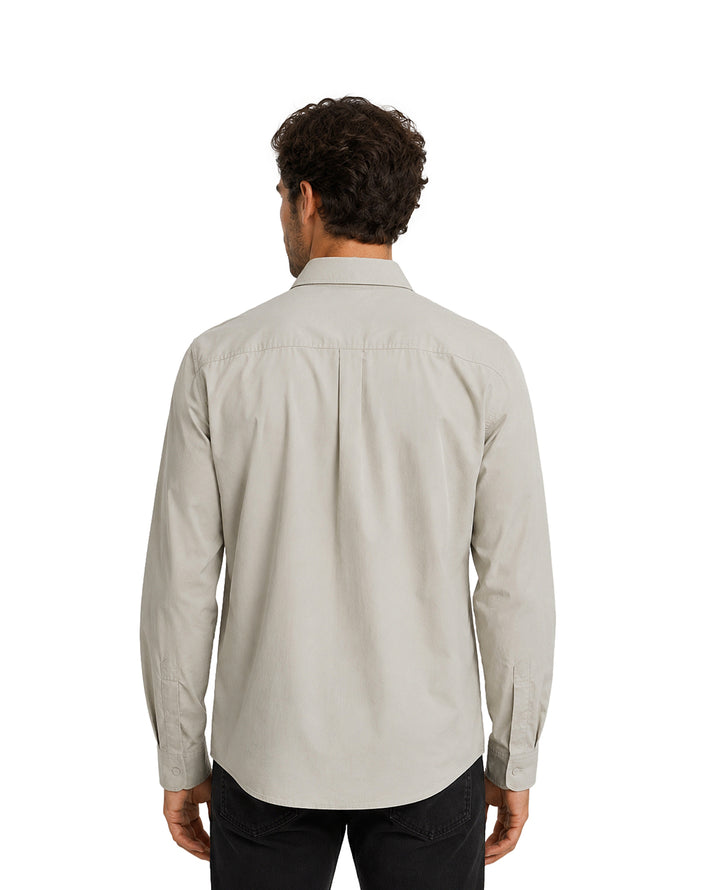 Hombre vistiendo una camisa gris de manga larga con cuello y bolsillo frontal.