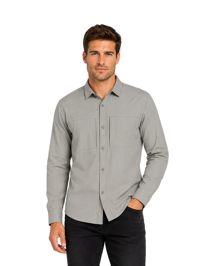 Hombre vistiendo una camisa gris de manga larga con botones y pantalones negros.