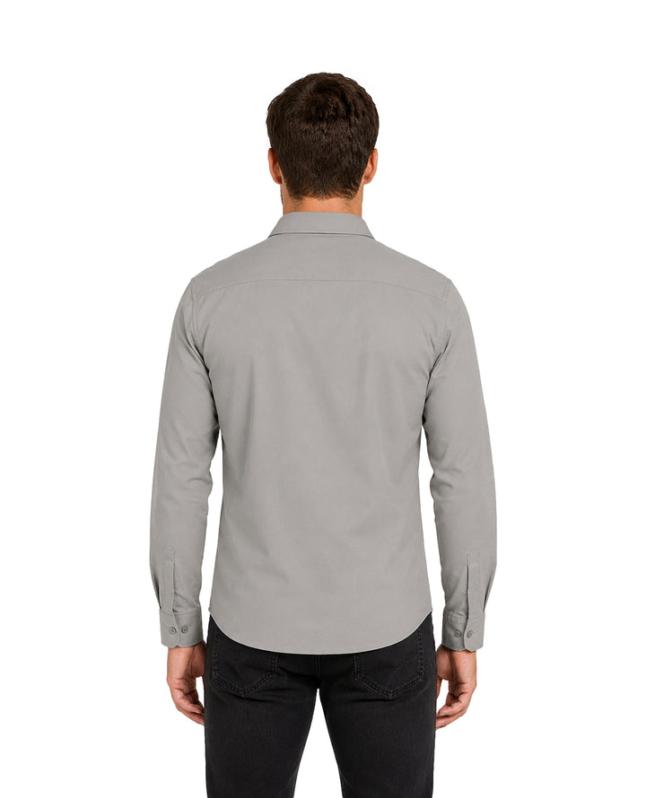 Hombre vistiendo una camisa gris de manga larga con botones y pantalones negros.