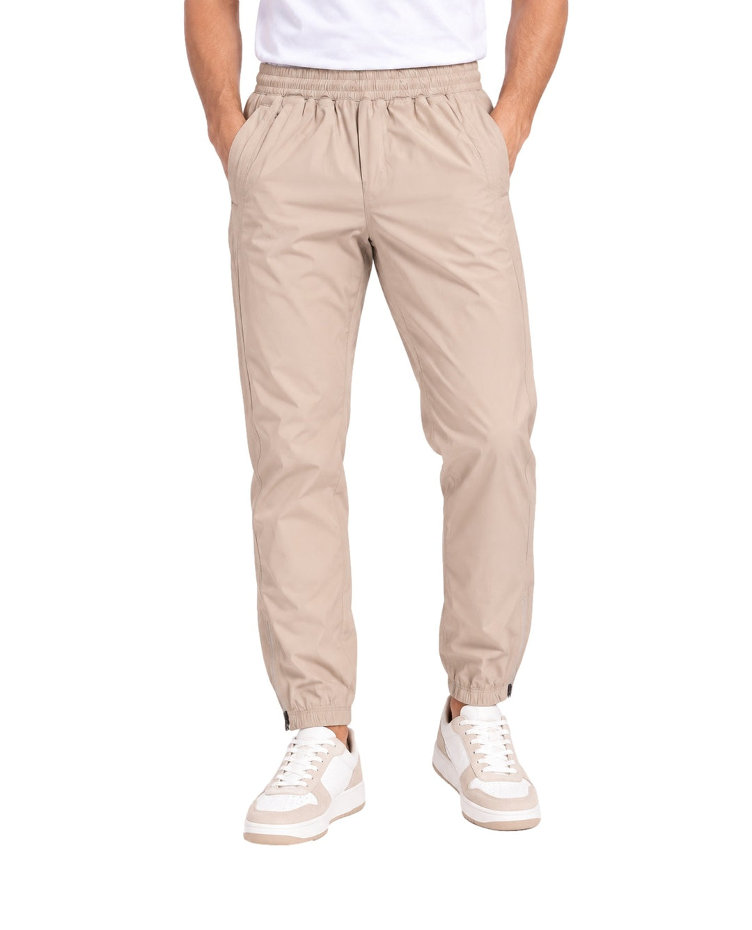 Hombre vistiendo pantalones jogger color beige de la marca UNGA con calzado blanco.