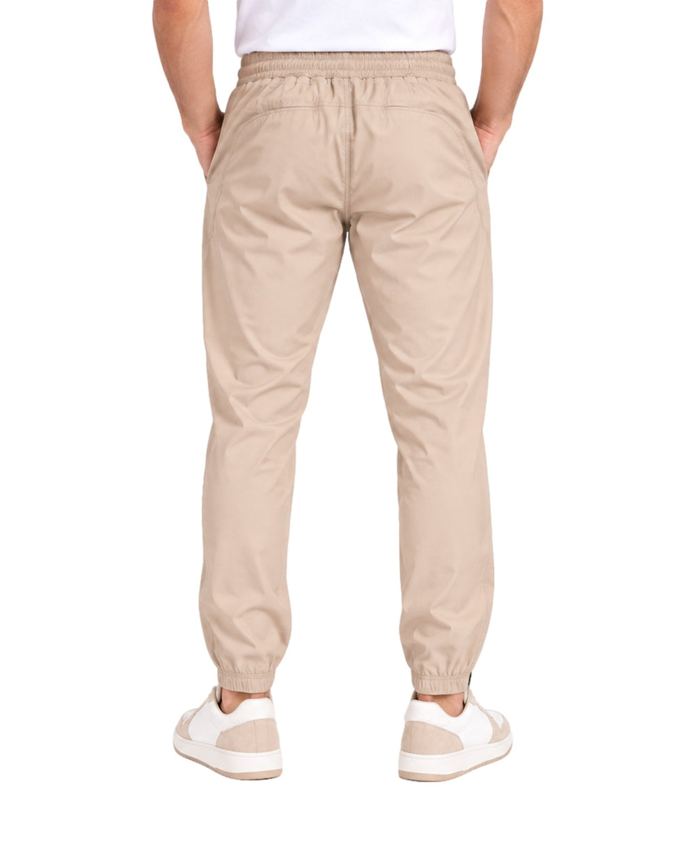 Hombre vistiendo pantalones jogger color beige de la marca UNGA con calzado blanco.