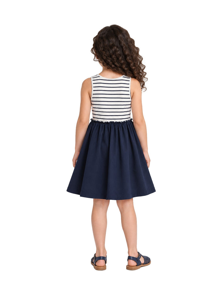 Niña vistiendo un vestido Zippy azul oscuro con parte superior a rayas blancas y azules y sandalias azules.