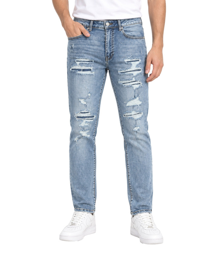 Hombre vistiendo jeans Kahua color azul medio con detalles desgastados y rotos en las piernas.