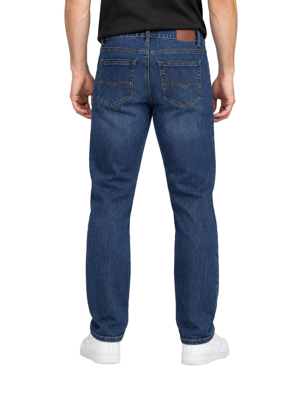 Hombre vistiendo jeans rectos de color índigo con tenis blancos sobre fondo blanco.