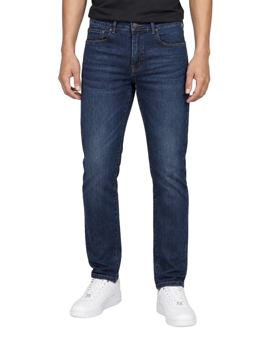 Hombre vistiendo jeans rectos de color índigo con tenis blancos sobre fondo blanco.