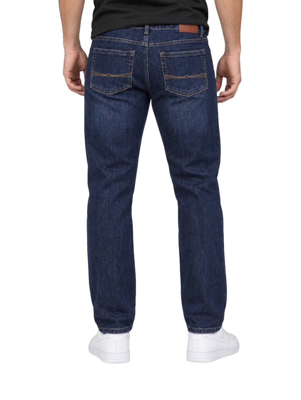 Hombre vistiendo jeans rectos de color índigo con tenis blancos sobre fondo blanco.