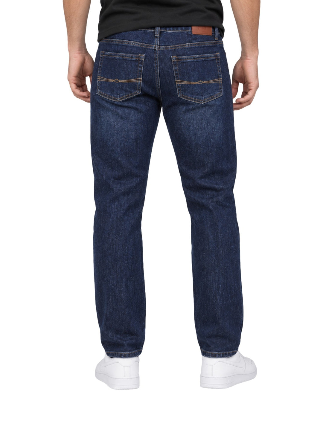 Hombre vistiendo jeans rectos de color índigo con tenis blancos sobre fondo blanco.