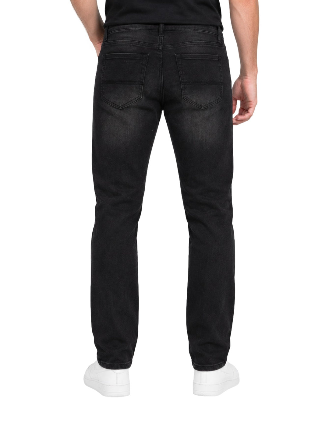 Hombre vistiendo jeans Kahua de color negro con calzado blanco sobre fondo blanco.