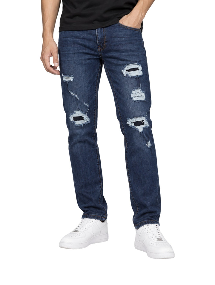 Hombre vistiendo jeans Kahua de color azul oscuro con detalles rotos y desgastados en las piernas.