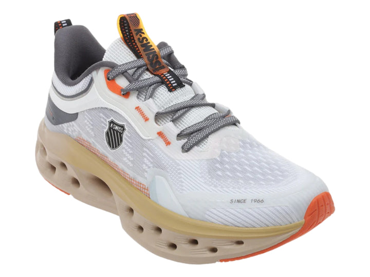 Tenis deportivos K-Swiss color blanco y arena con suela gruesa perforada y detalles en naranja.