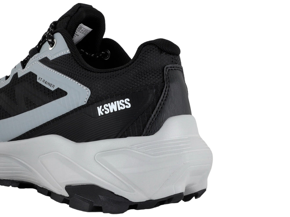 Tenis deportivos K-Swiss color negro y gris con suela gruesa y cordones moteados.