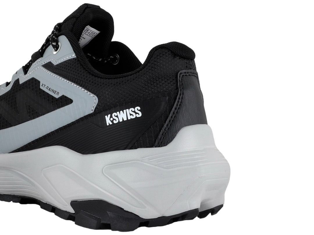 Tenis deportivos K-Swiss color negro y gris con suela gruesa y cordones moteados.