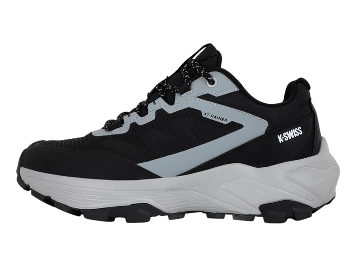 Tenis deportivos K-Swiss color negro y gris con suela gruesa y cordones moteados.