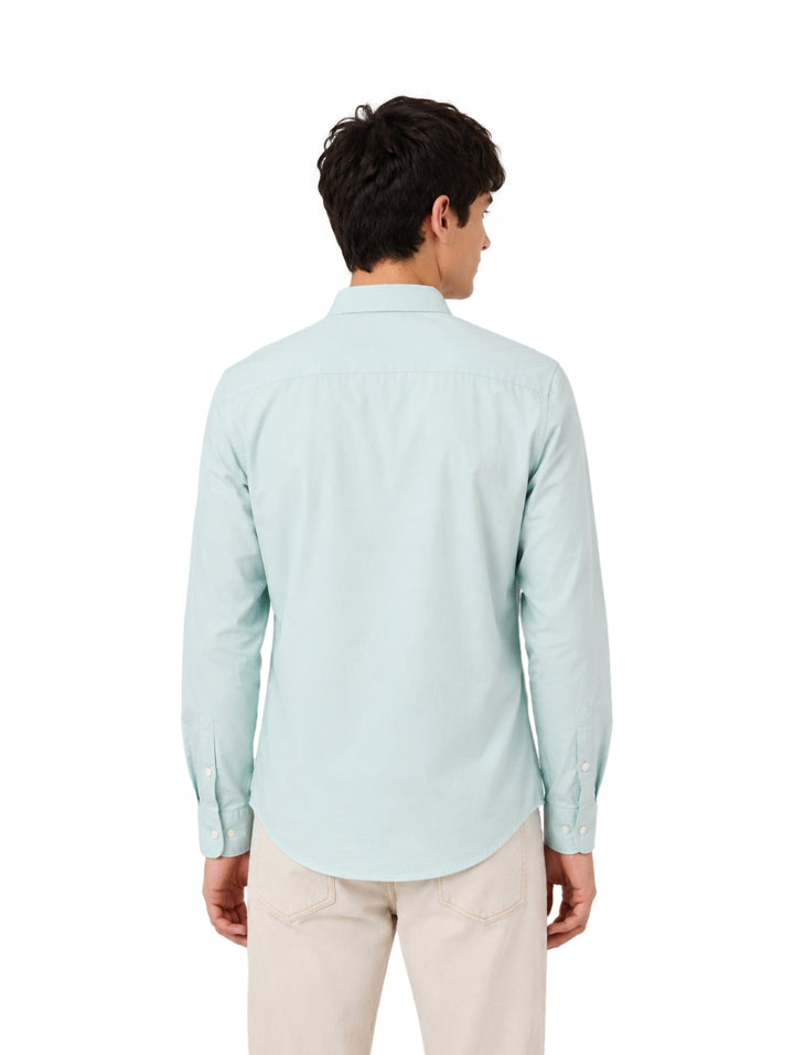 Hombre vistiendo una camisa de color menta de manga larga y pantalones beige.