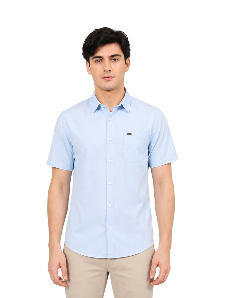 Hombre vistiendo una camisa de manga corta color azul claro y pantalones beige.