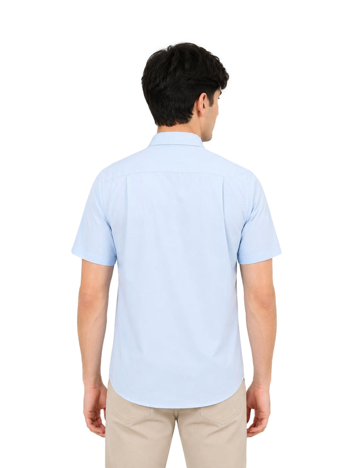 Hombre vistiendo una camisa de manga corta color azul claro y pantalones beige.