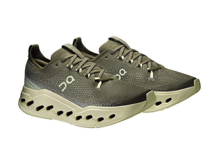 Tenis deportivos On Cloud color verde oliva con suela gruesa y perforada en tono verde claro.