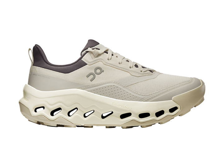 Tenis deportivos On Cloud color beige con suela gruesa y cuello en color gris oscuro.