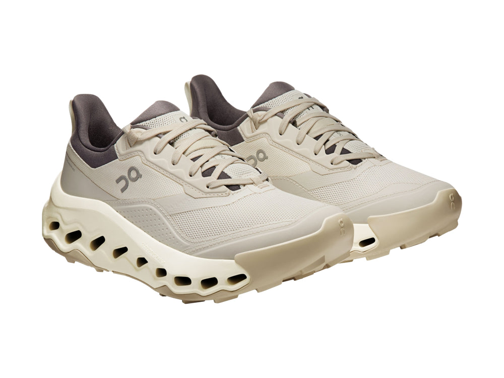 Tenis deportivos On Cloud color beige con suela gruesa y cuello en color gris oscuro.