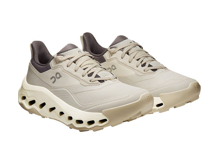 Tenis deportivos On Cloud color beige con suela gruesa y cuello en color gris oscuro.