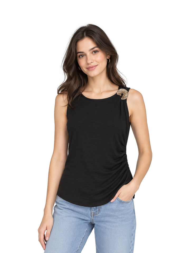 Mujer vistiendo una blusa negra sin mangas con un detalle decorativo dorado en el hombro.