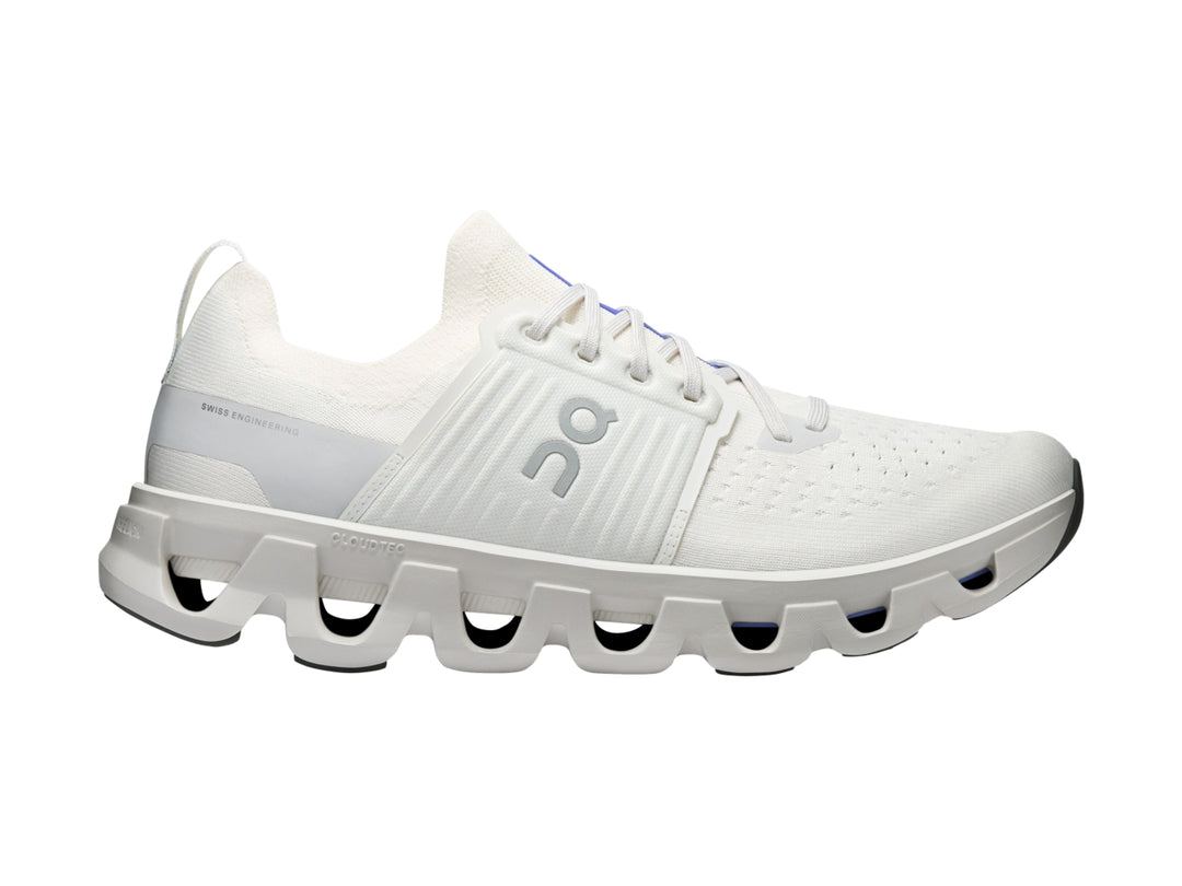 Tenis deportivos On Cloud color blanco ivory con suela amortiguada característica y detalles azules.