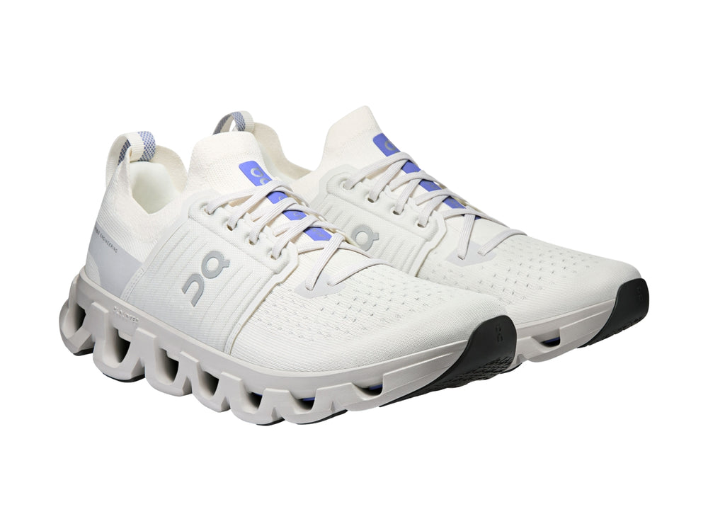 Tenis deportivos On Cloud color blanco ivory con suela amortiguada característica y detalles azules.