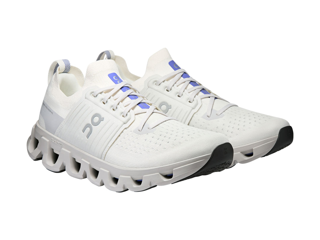Tenis deportivos On Cloud color blanco ivory con suela amortiguada característica y detalles azules.